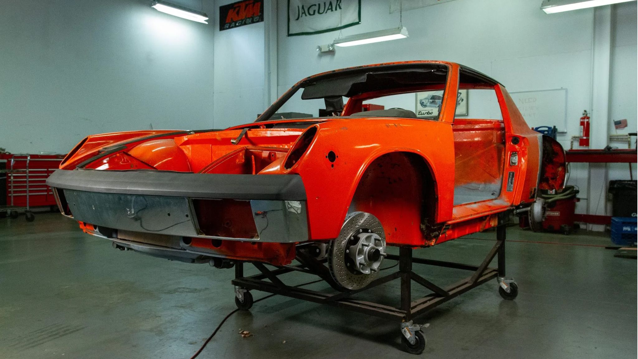 A red 1974 Porsche 914 on a body stand in garage