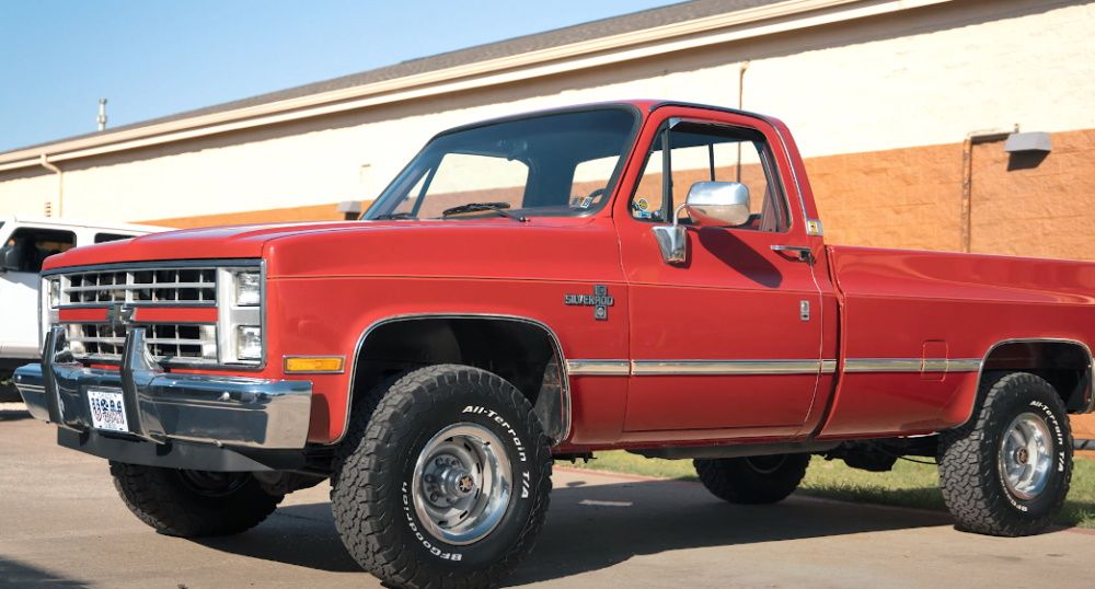 A red 1987 Chevrolet Silverado outside of a building, front