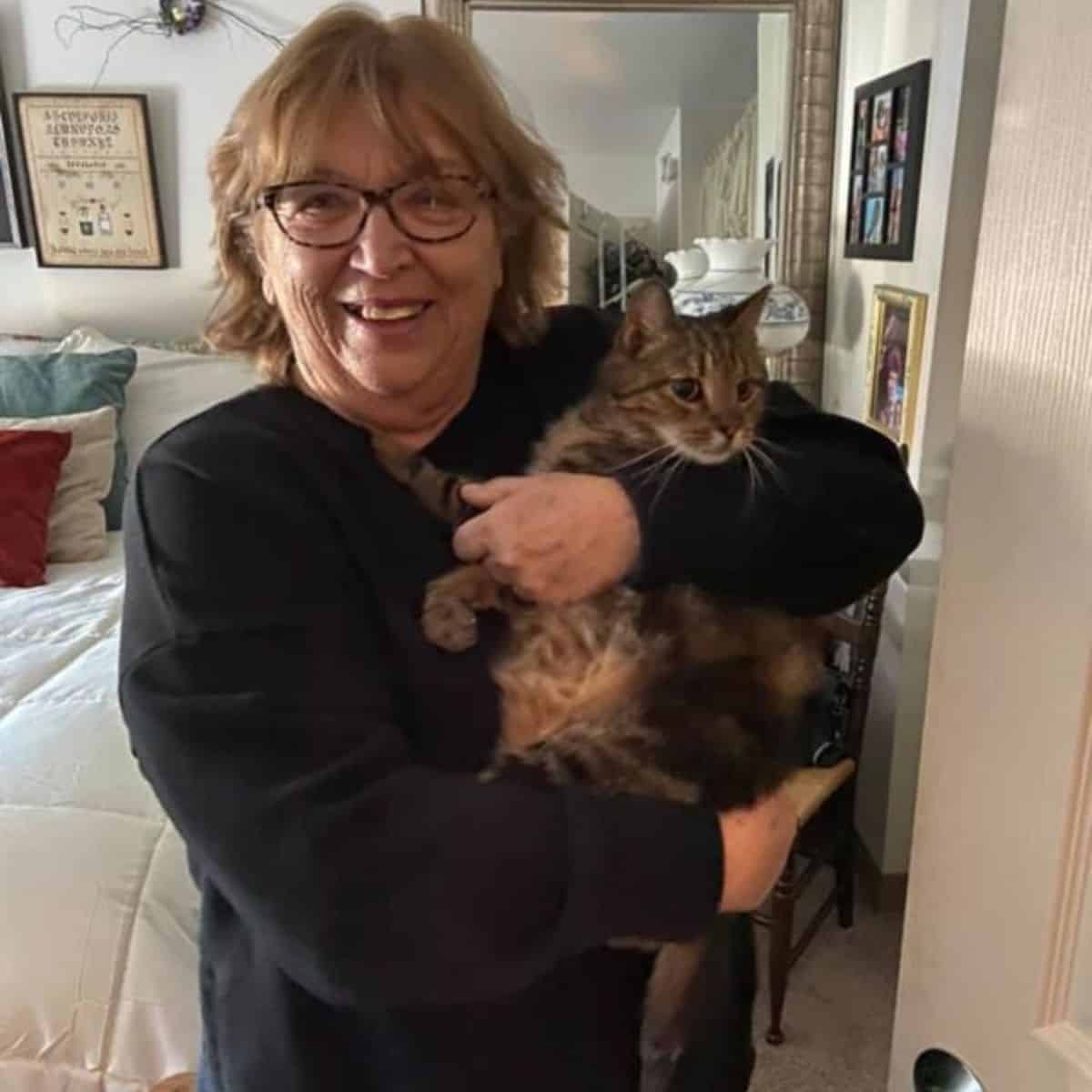 an elderly woman holds a cat in her arms