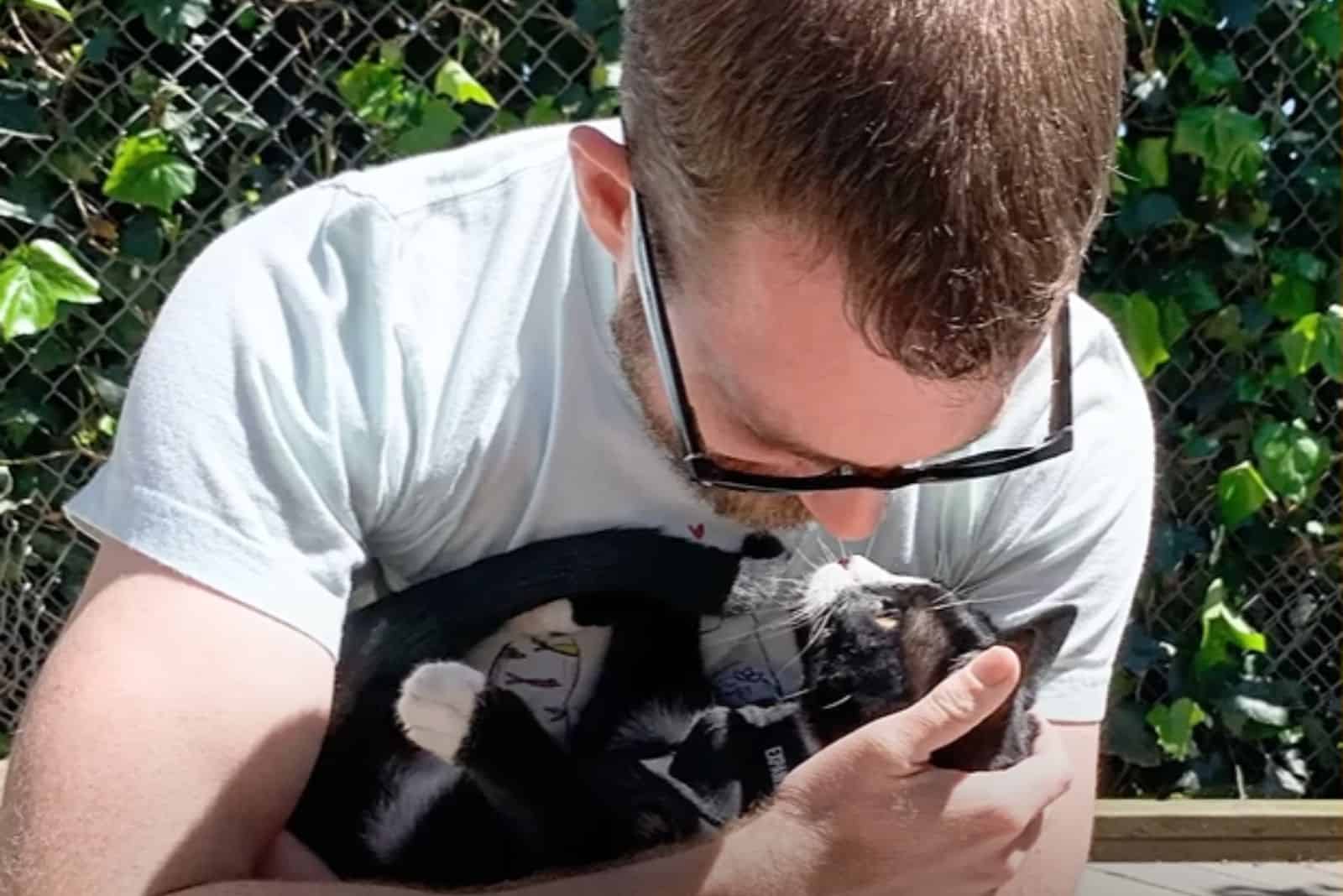 man cuddling with cat