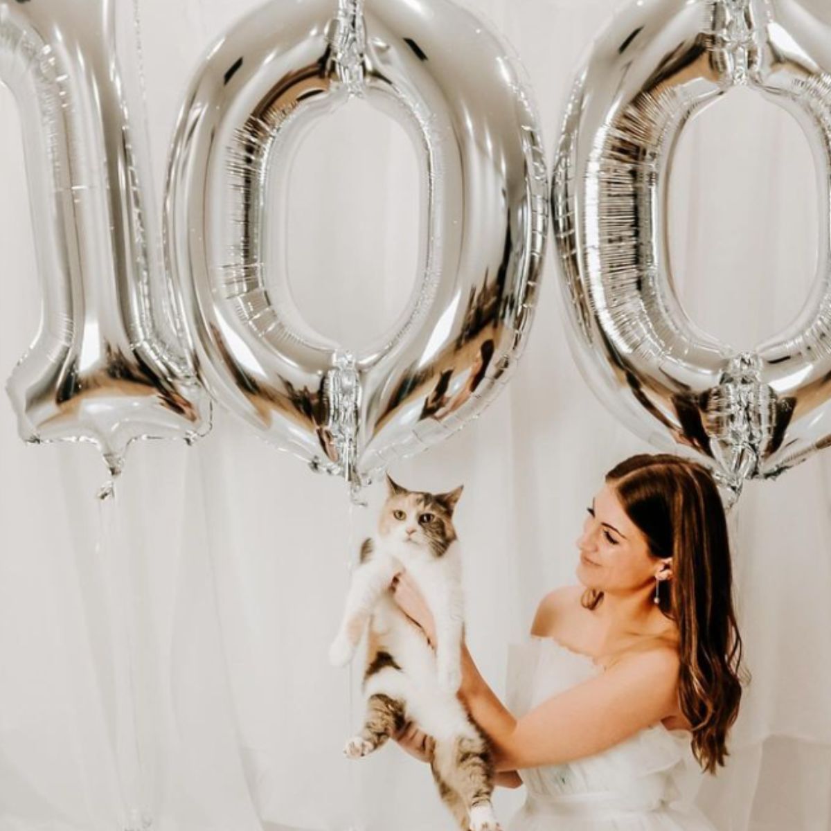 woman hold cat in fron of balloons