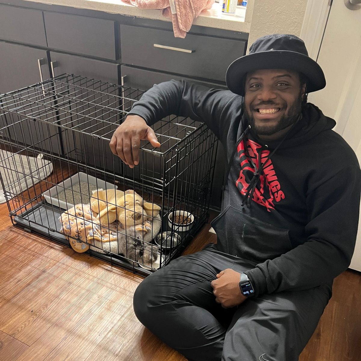 smiling man posing with kitten in cage